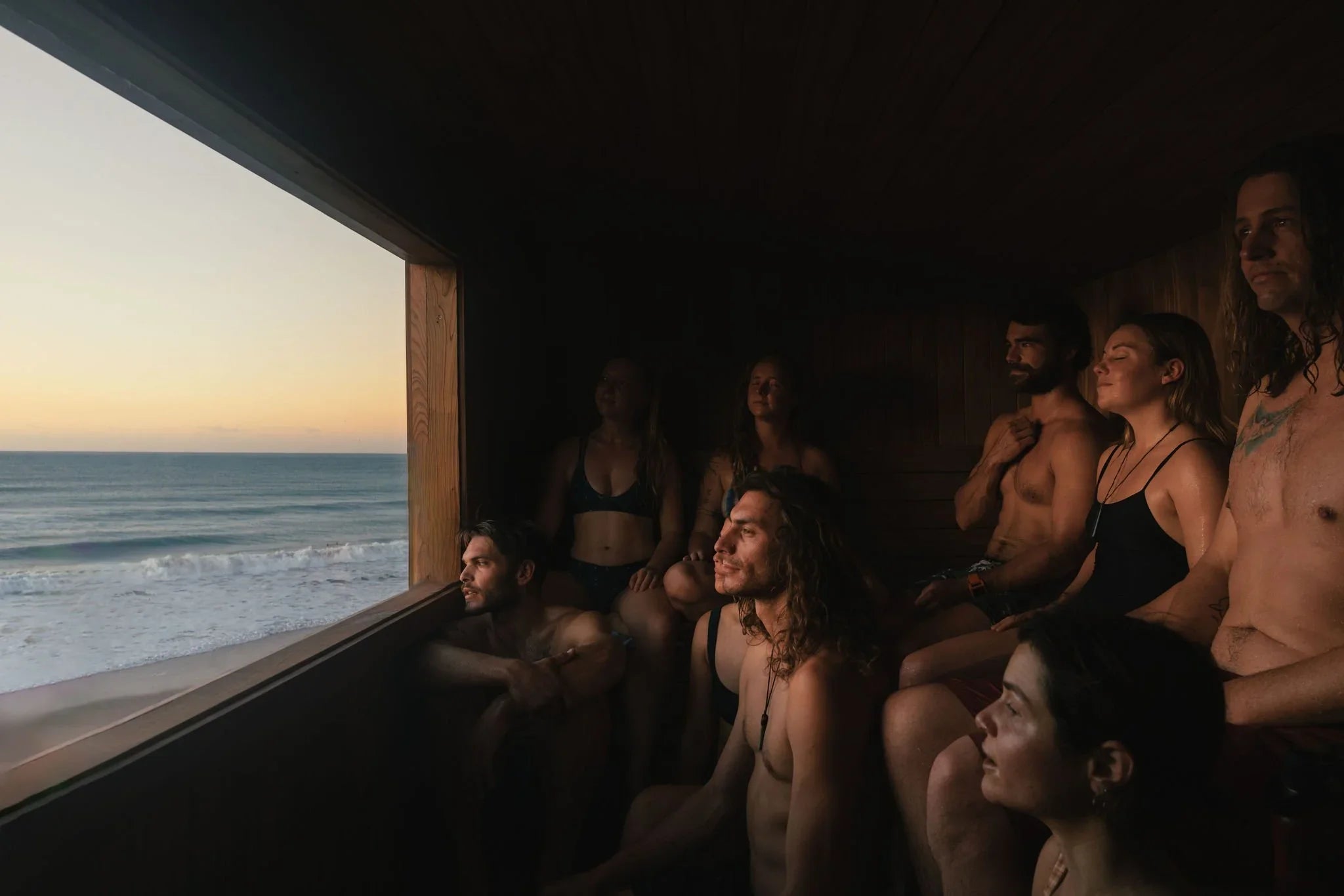 Group in beachside sauna watching sunset — why head temperature matters in sauna