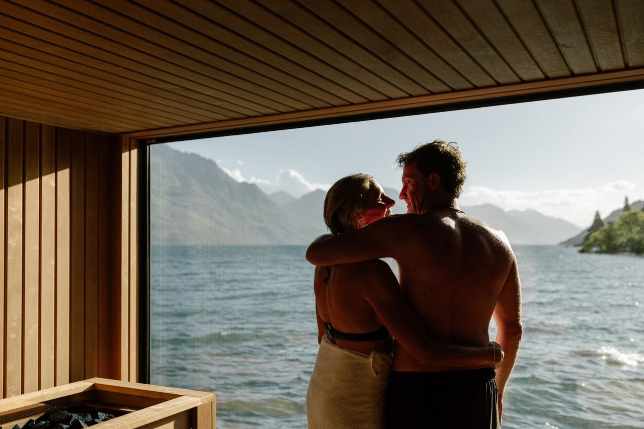 Couple embracing in sauna overlooking lake and mountains — sauna for mental health
