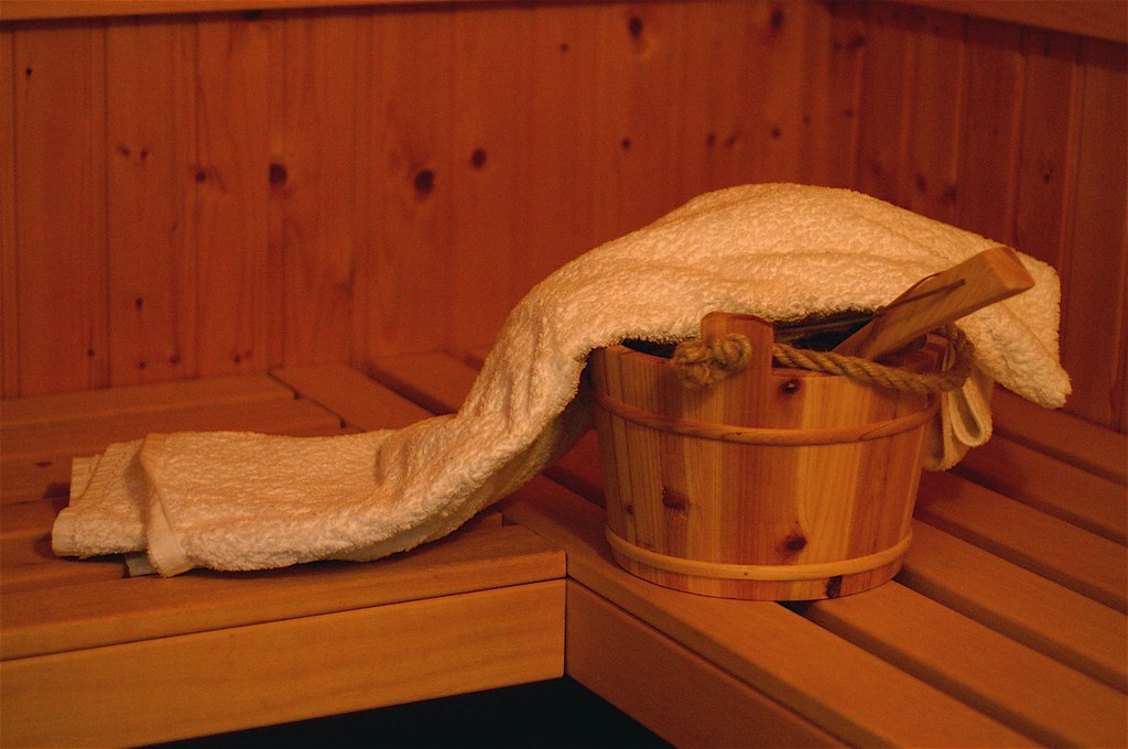 Sauna bucket and ladle on wooden bench — best sauna hat guide 2026
