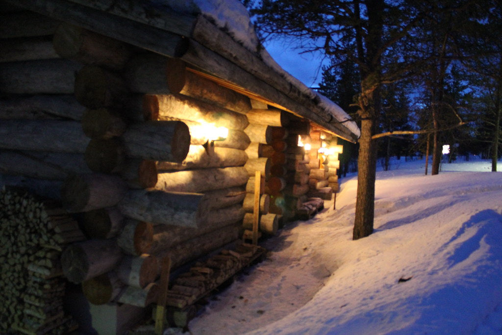 Log sauna cabin at twilight in snow — staying longer in the sauna with a hat