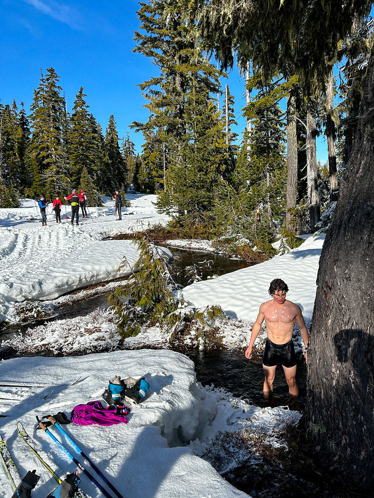 Man cold plunging in snowy stream — sauna before or after workout