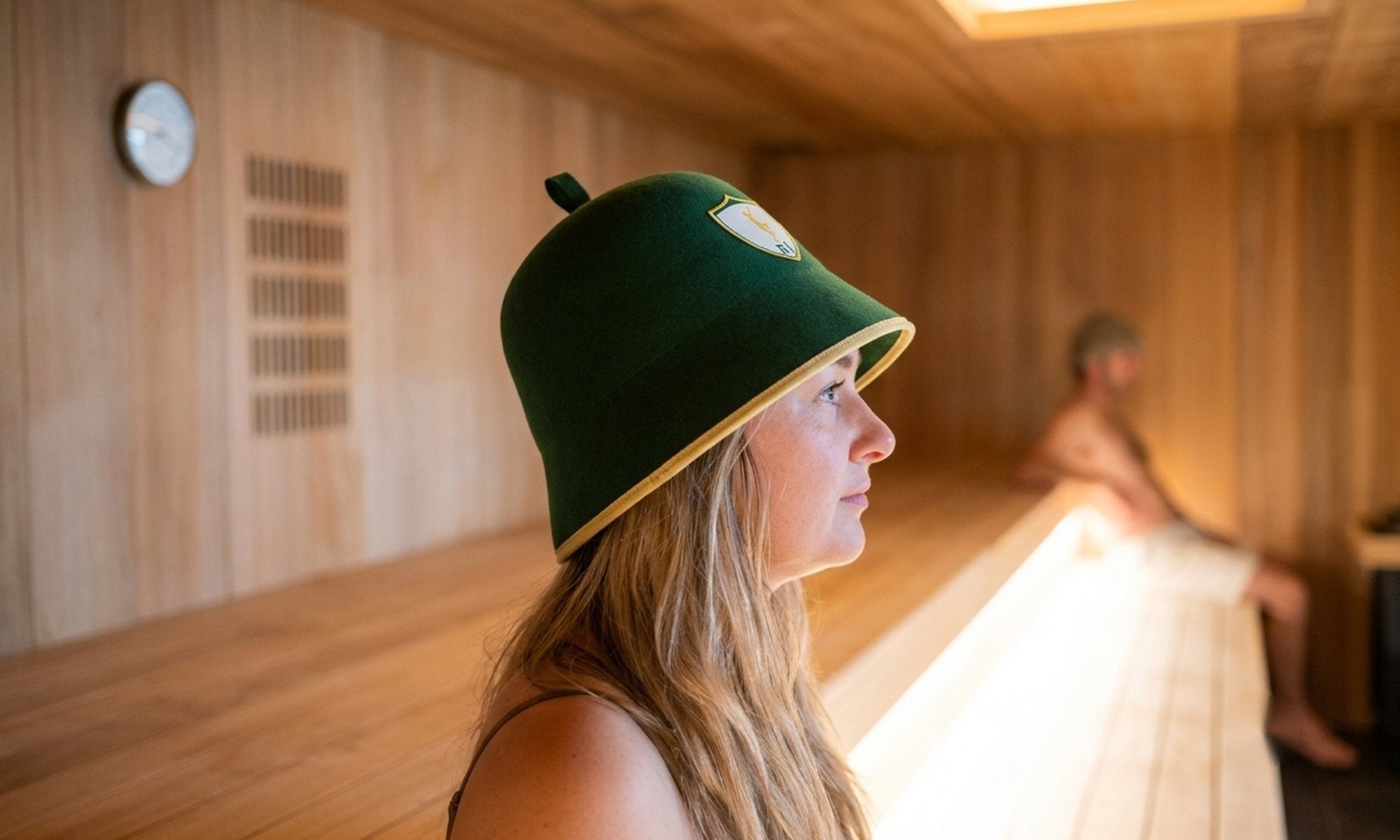 Best sauna hat: woman wearing a green wool felt Rí Sauna Crown hat in a cedar sauna