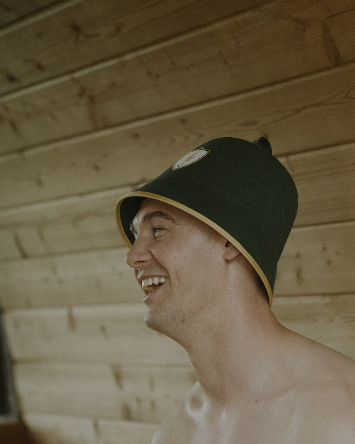 Man laughing in a barrel sauna wearing the Rí Sauna Crown